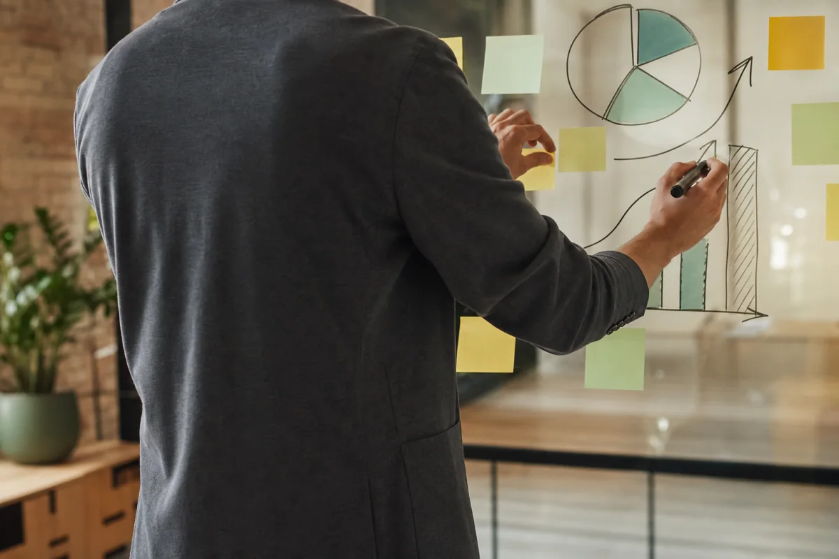 Seseorang dari belakang menyusun strategi bisnis di papan